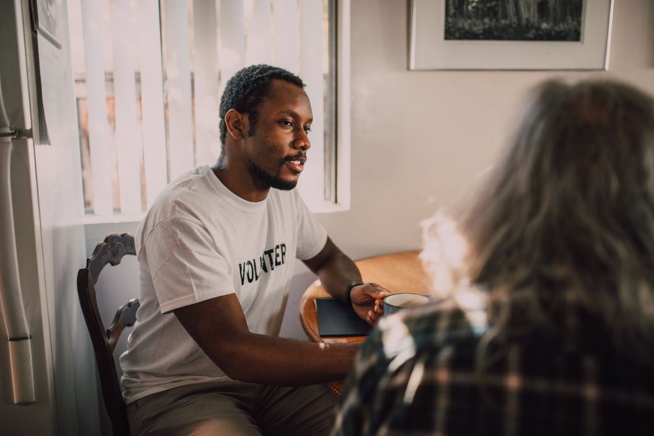Two people sharing a supportive conversation in a warm, quiet room - spouse grief support group